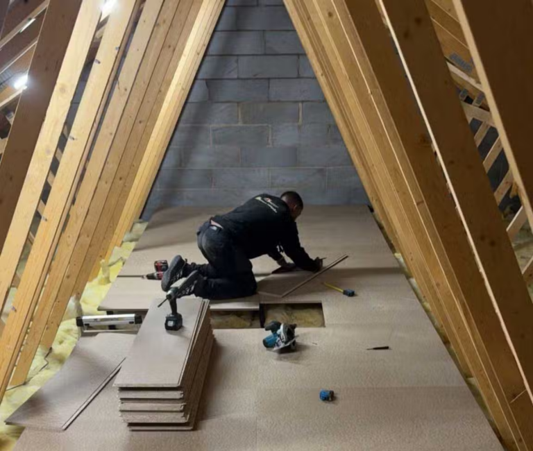 An installer fitting raised loft boarding between roof timbers